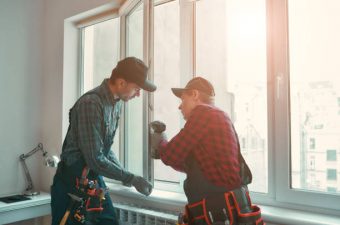 Portrait of mature men wearing uniform standing indoors and installing new windows in the apartment. Horizontal shot
